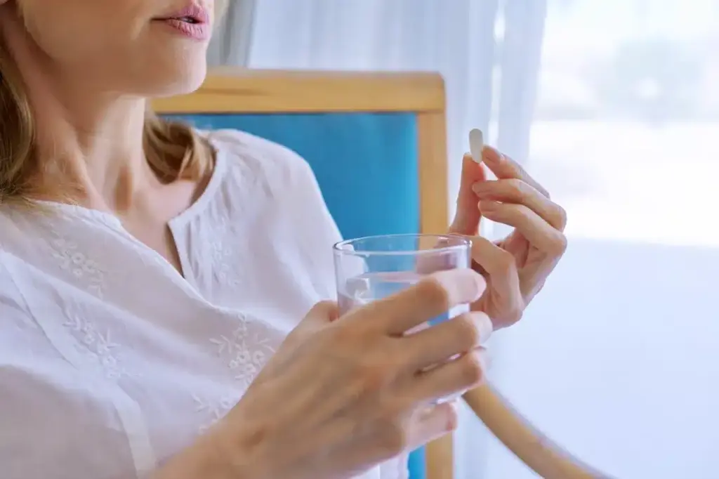 Woman holding pill and water indoors during the da 2026 01 07 02 25 36 utc groot